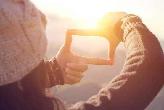 Kvinna ramar in en solnedgång med sina händer